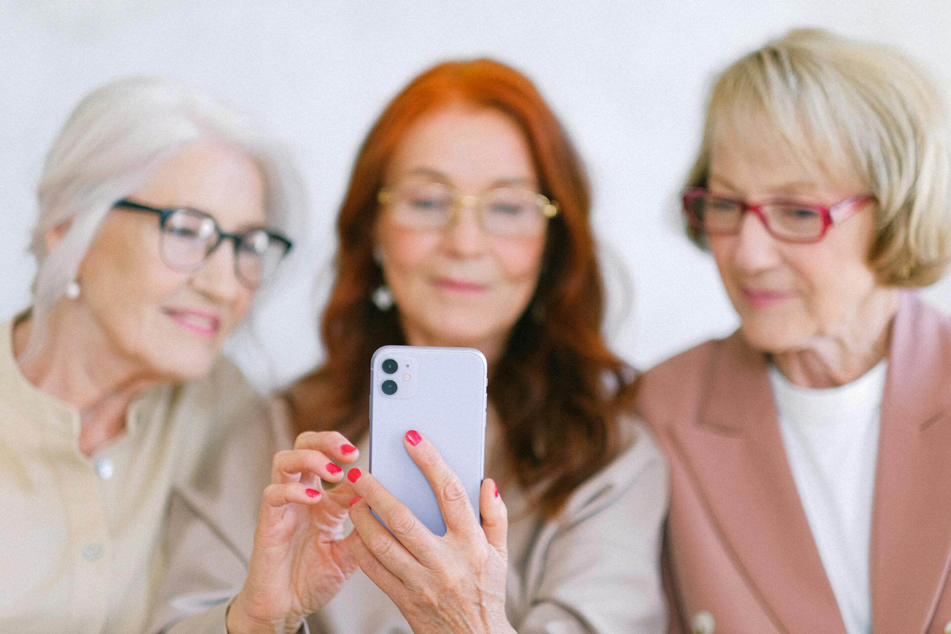 Tre äldre damer som använder artificiell intelligens på mobilen.